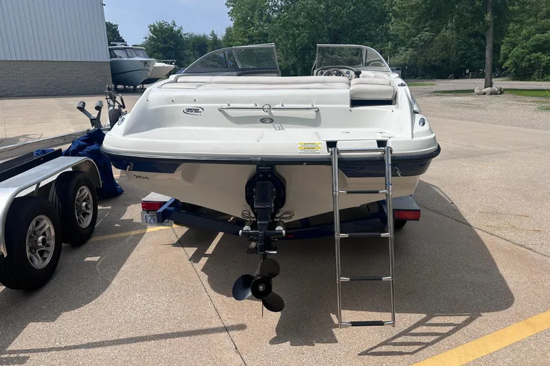 Slide: The Image of 2015 Crownline 21 SS boat with ladder, parked on a trailer in a sunny outdoor setting. - 6