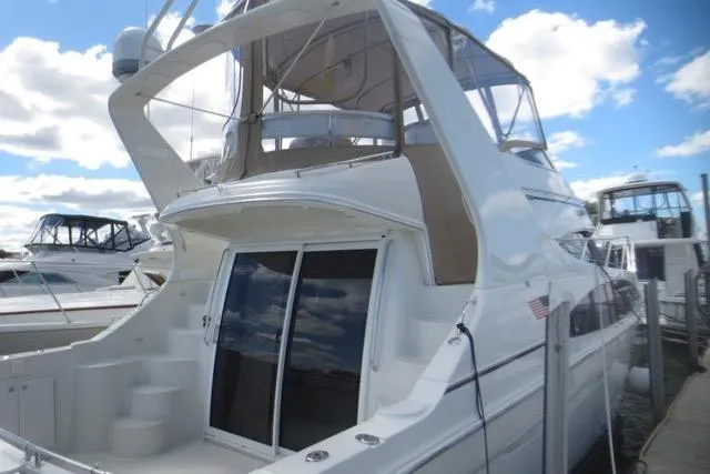Slide: The Image of 2004 Carver 420 Mariner yacht docked, showcasing sleek design and spacious upper deck. - 4