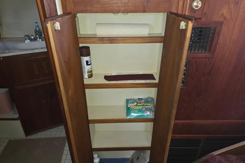 Slide: The Image of Open wooden cabinet in 1988 Marinette 37 Motor Yacht, containing cleaning supplies and odor eliminator. - 32