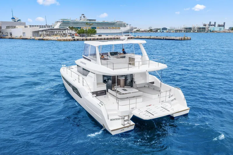 Slide: The Image of 2025 Leopard 53 Powercat yacht cruising in a vibrant blue harbor near a docked cruise ship. - 2