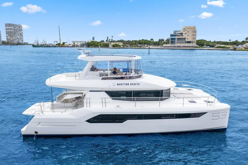 Slide: The Image of 2025 Leopard 53 Powercat yacht cruising on blue waters near a coastal city. - 5