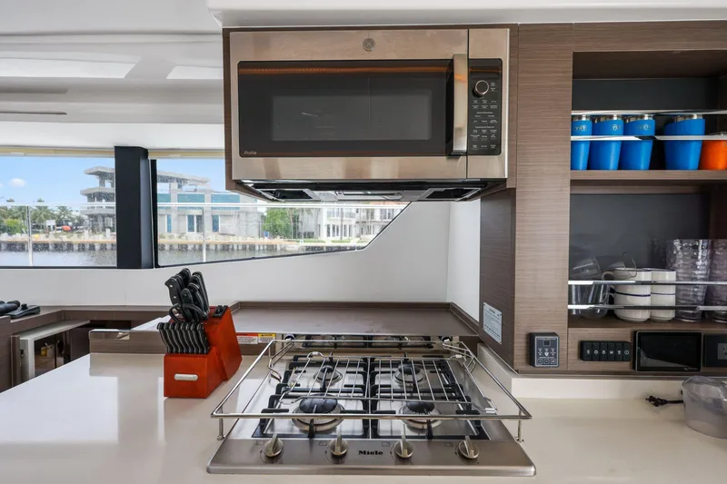 Slide: The Image of Modern kitchen interior on 2025 Leopard 53 Powercat yacht, featuring stove, microwave, and storage shelves. - 65