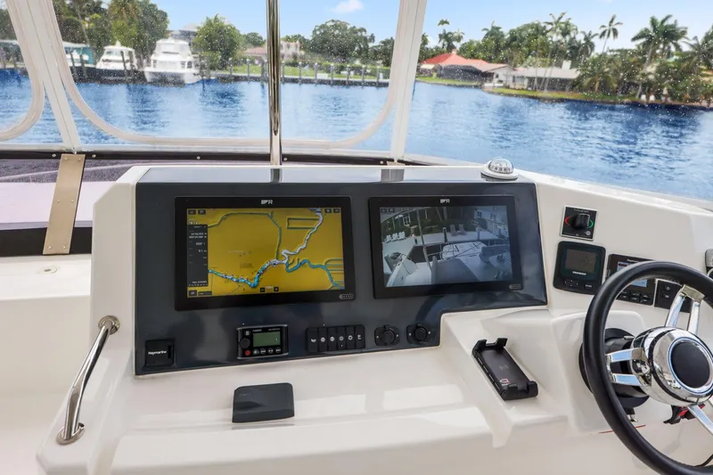Slide: The Image of Helm of 2025 Leopard 53 Powercat with navigation screens and steering wheel, overlooking waterway. - 80