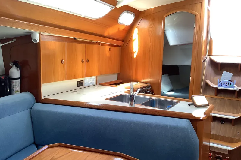 Slide: The Image of Interior of 1997 Jeanneau Sun Odyssey 36.2 yacht, featuring a cozy kitchen and seating area. - 9
