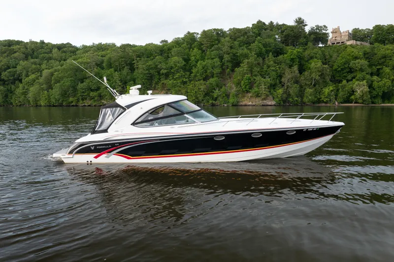 The Image of 2006 Formula 400 Super Sport boat cruising on a scenic river with lush green forest backdrop. - 1