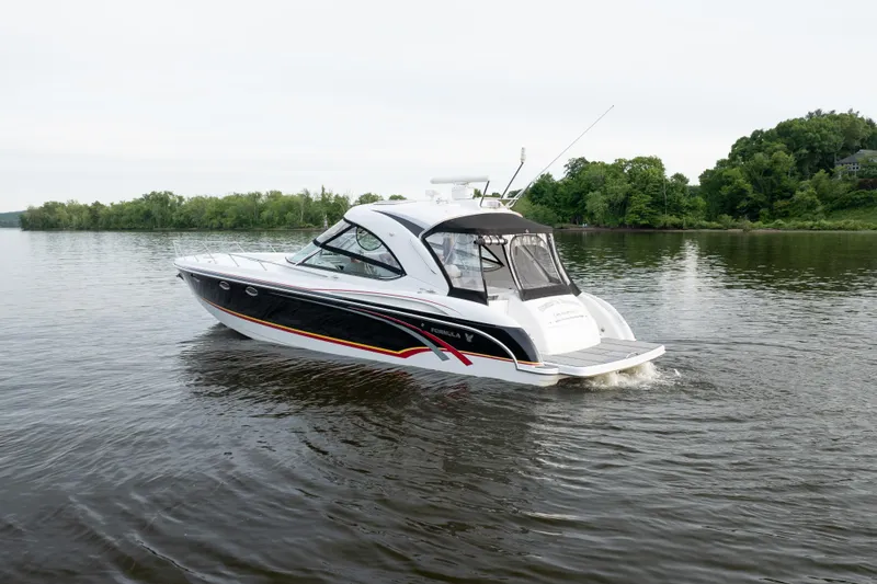 Slide: The Image of 2006 Formula 400 Super Sport boat cruising on a calm lake with lush green shoreline. - 6