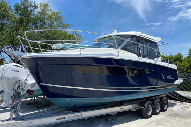 The Image of 2024 Jeanneau NC Weekender 895 Series 2 boat on trailer, sunny day, trees in background. - 0