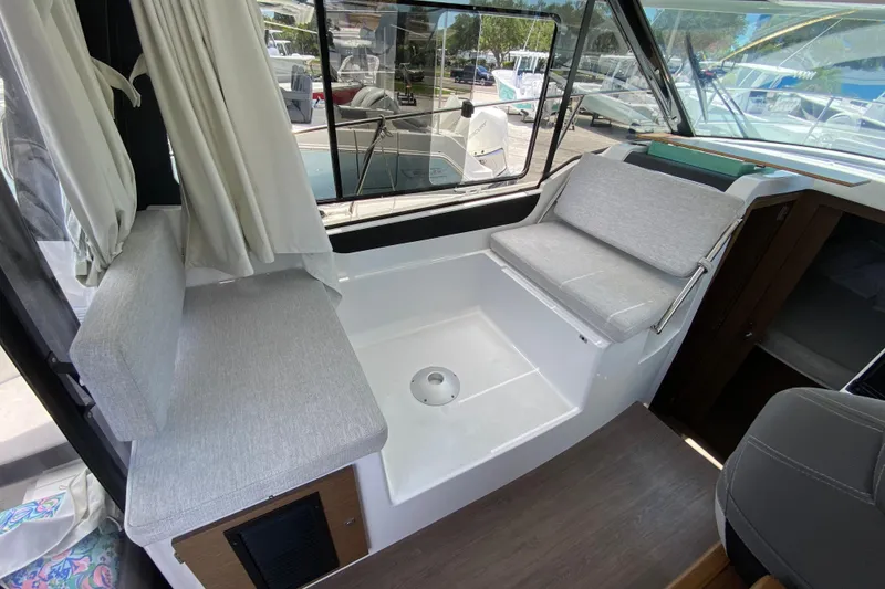 Slide: The Image of 2024 Jeanneau NC Weekender 895 Series 2 interior with cushioned seating and large windows. - 11