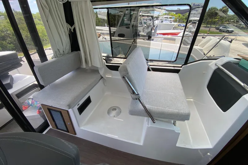 Slide: The Image of Interior of 2024 Jeanneau NC Weekender 895 Series 2, featuring modern seating and large windows. - 12