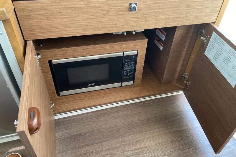 Slide: The Image of 2024 Jeanneau NC Weekender 895 Series 2 interior with built-in microwave in wooden cabinet. - 28
