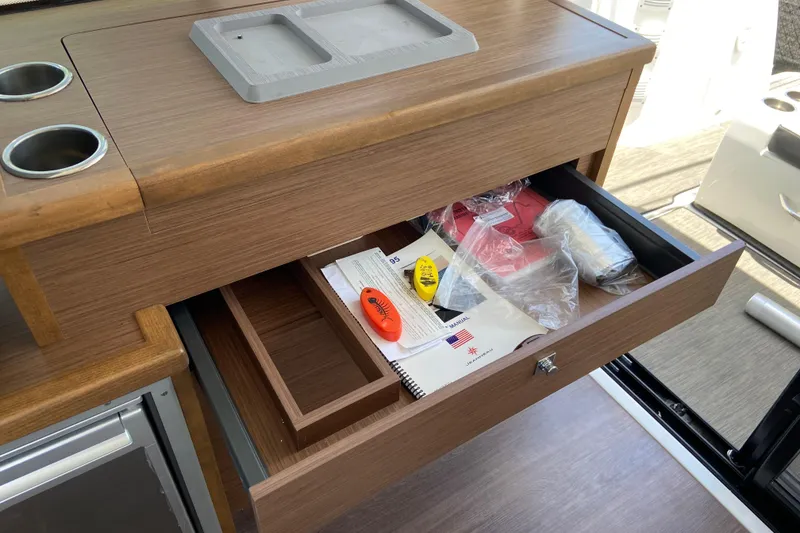 Slide: The Image of Open drawer in 2024 Jeanneau NC Weekender 895 Series 2, showing manuals and accessories. - 29
