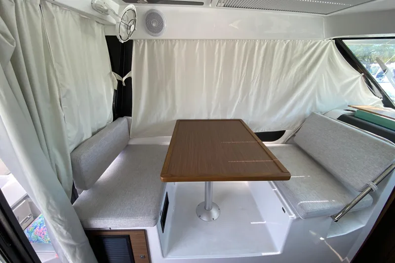 Slide: The Image of Interior of 2024 Jeanneau NC Weekender 895 Series 2, featuring a cozy dining area with curtains. - 7
