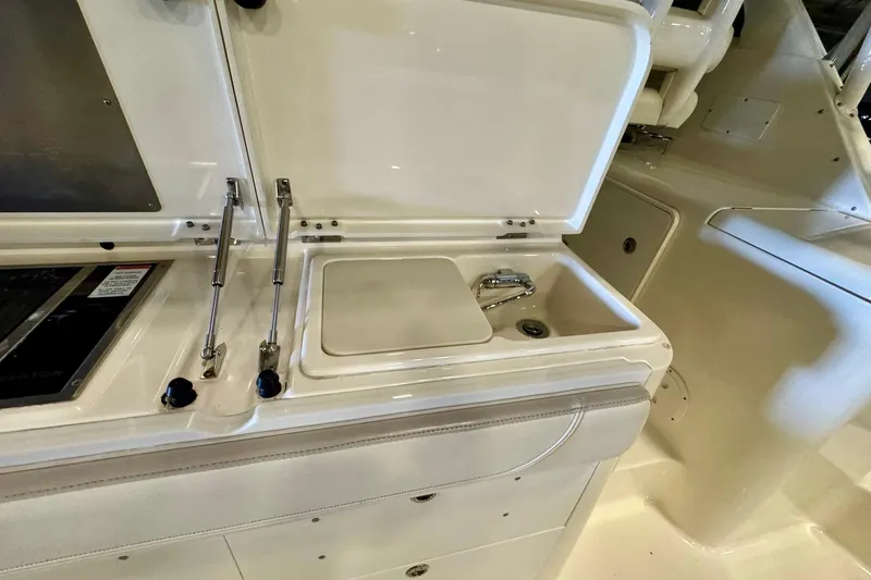 Slide: The Image of 2014 Pursuit OS 345 Offshore boat interior with sink and storage compartments. - 14