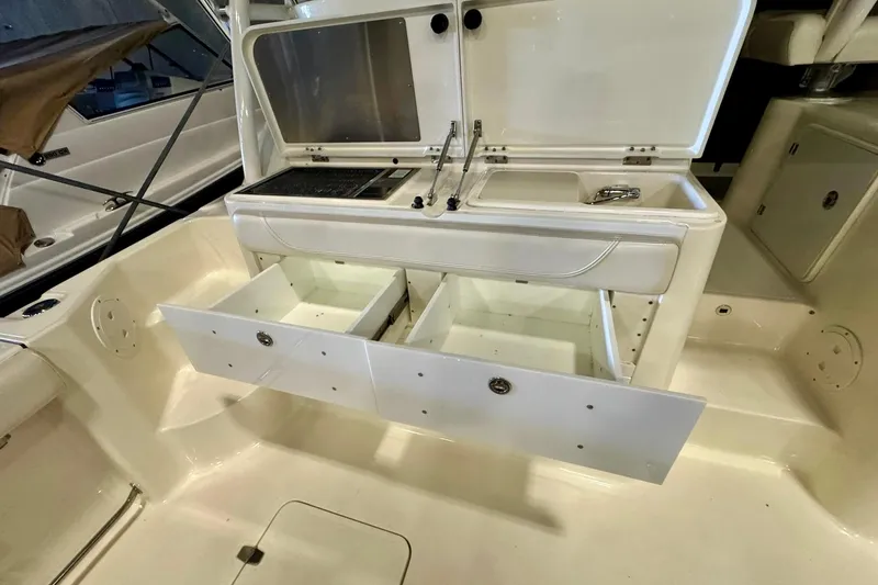 Slide: The Image of 2014 Pursuit OS 345 Offshore boat interior with open storage compartments and sink. - 15