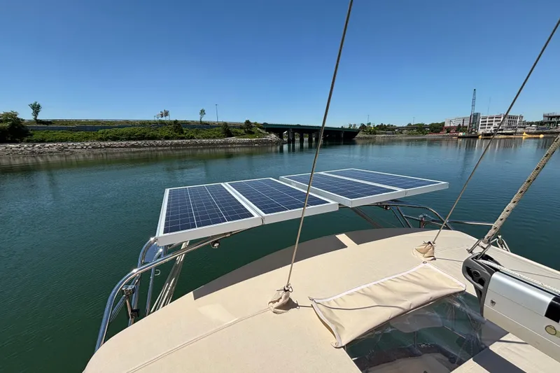 Slide: The Image of 2015 Island Packet 370 sailboat with solar panels on deck, docked by a calm river. - 18