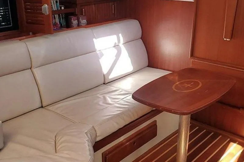 Slide: The Image of Interior of 2015 Island Packet 370 yacht with white seating and wooden table. - 28