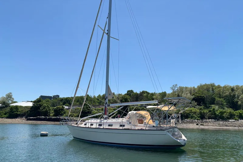 Slide: The Image of 2015 Island Packet 370 sailboat anchored in calm waters, surrounded by lush greenery. - 3