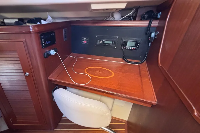 Slide: The Image of Navigation station inside 2015 Island Packet 370 sailboat with wooden desk and communication equipment. - 41