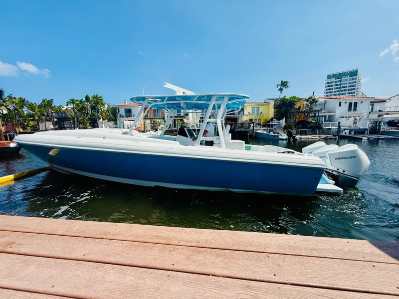 The Image of 2003 Intrepid 377 boat docked in a sunny marina, featuring a sleek blue and white design. - 0