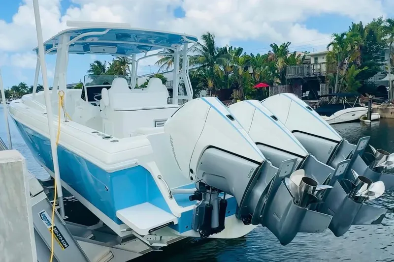 Slide: The Image of 2003 Intrepid 377 boat with triple outboard engines docked by a tropical waterfront. - 106