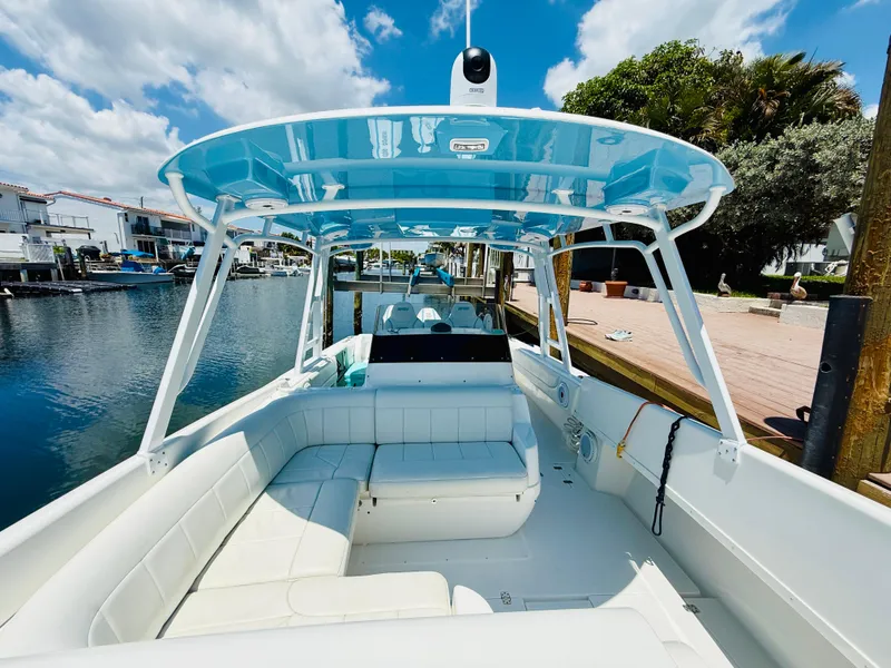 Slide: The Image of 2003 Intrepid 377 boat with blue canopy, docked in a scenic waterfront area. - 13