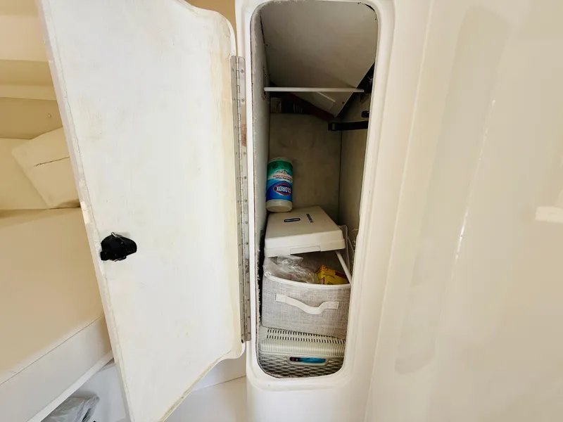Slide: The Image of Storage compartment on a 2003 Intrepid 377 boat, containing cleaning supplies and a basket. - 20