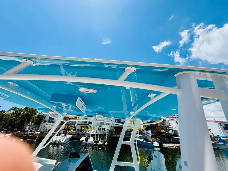 Slide: The Image of 2003 Intrepid 377 boat with blue canopy, docked under clear sky. - 31