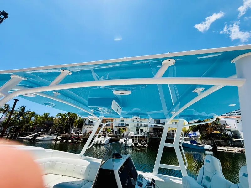 Slide: The Image of 2003 Intrepid 377 boat with blue canopy, docked in a sunny marina. - 32