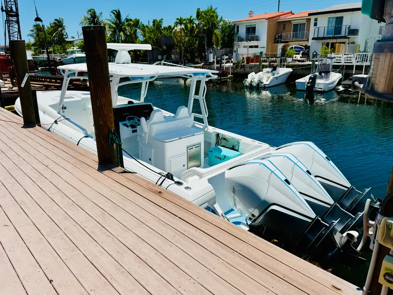 Slide: The Image of 2003 Intrepid 377 boat docked by waterfront homes, featuring triple outboard engines. - 4
