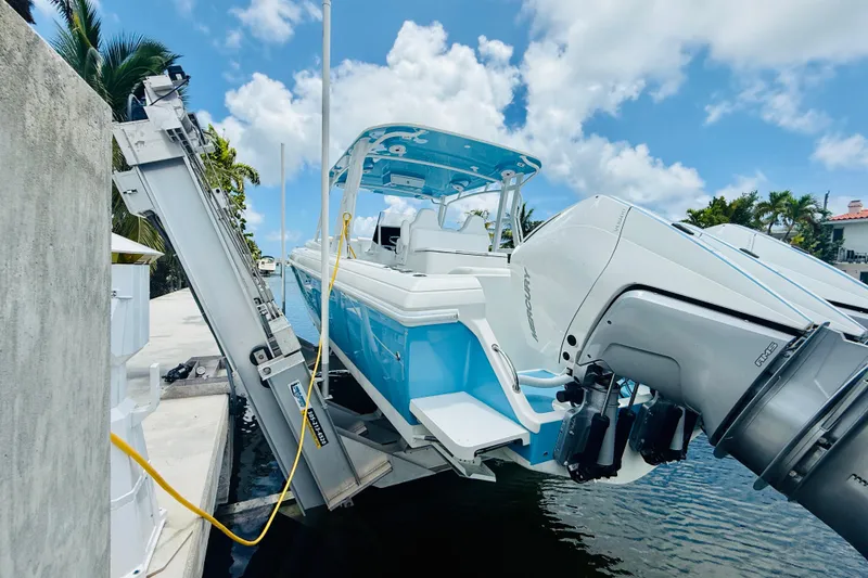 Slide: The Image of 2003 Intrepid 377 boat on lift, docked by palm trees under a blue sky. - 45