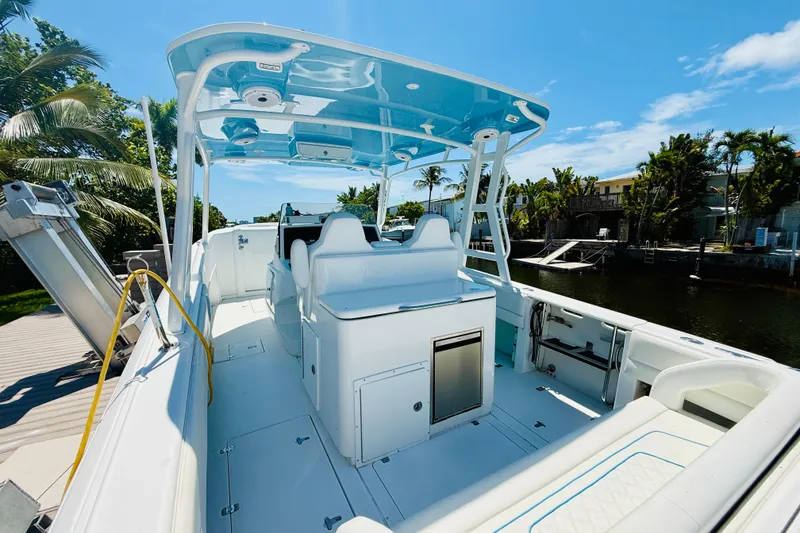 Slide: The Image of 2003 Intrepid 377 boat interior with sleek white seating and modern amenities, docked by a canal. - 51
