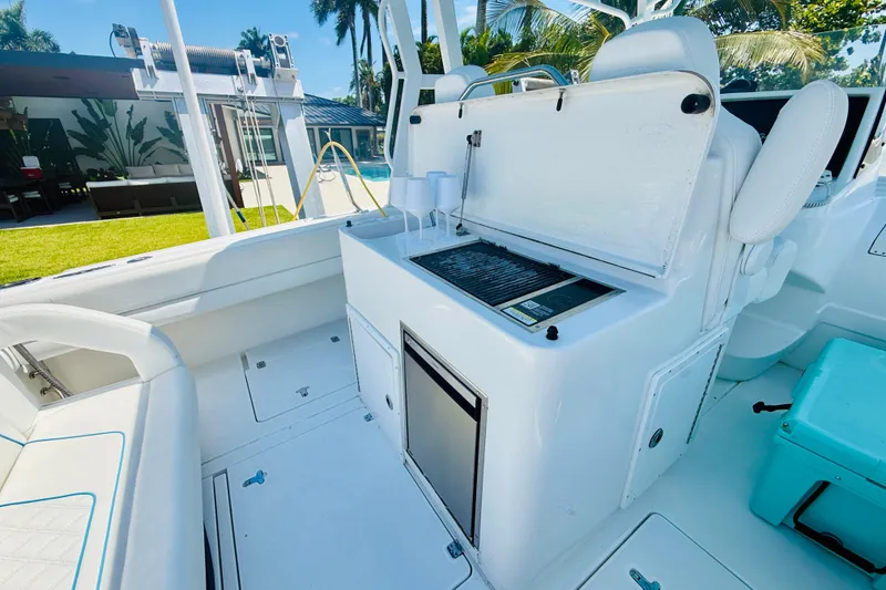 Slide: The Image of 2003 Intrepid 377 boat interior with grill and seating, surrounded by lush greenery. - 57