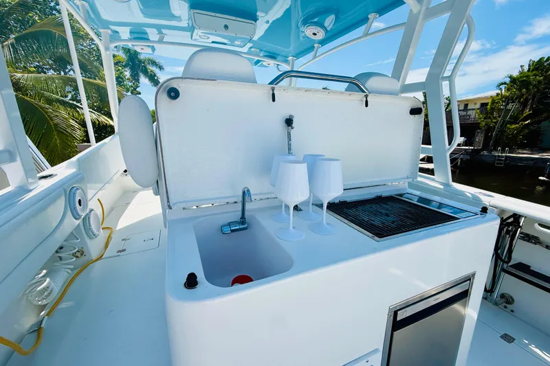 Slide: The Image of 2003 Intrepid 377 boat with sink, grill, and wine glasses on deck under blue sky. - 58