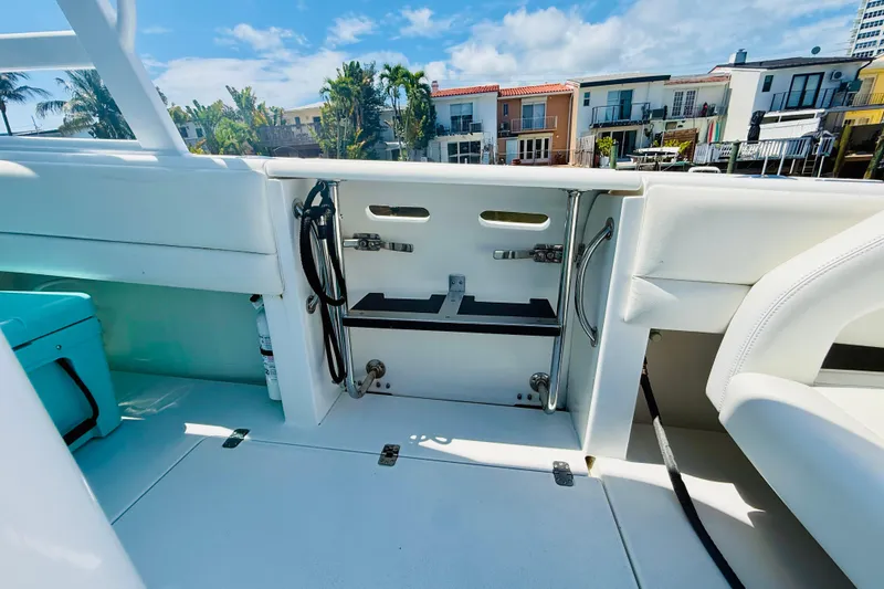 Slide: The Image of 2003 Intrepid 377 boat interior with white seating and storage, docked near waterfront homes. - 61