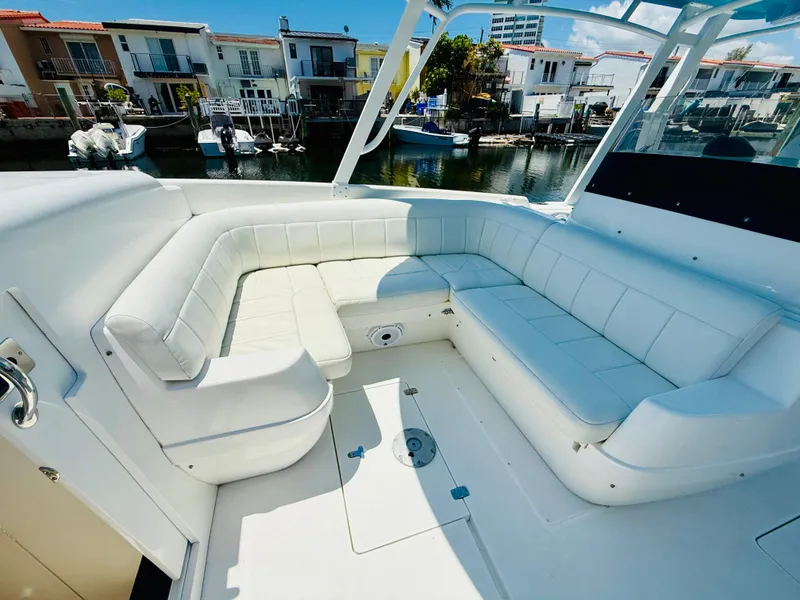 Slide: The Image of 2003 Intrepid 377 boat with spacious white seating area, docked near waterfront homes. - 75