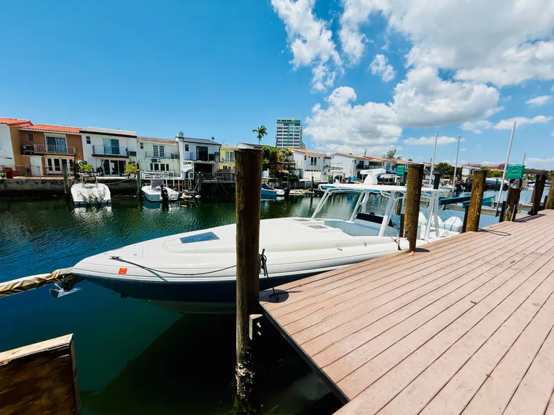Slide: The Image of 2003 Intrepid 377 boat docked by waterfront homes under a clear blue sky. - 8