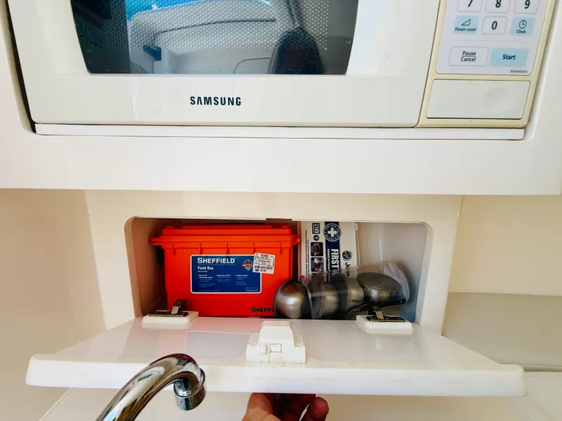 Slide: The Image of Storage compartment in a 2003 Intrepid 377 boat, featuring a microwave and safety equipment. - 82