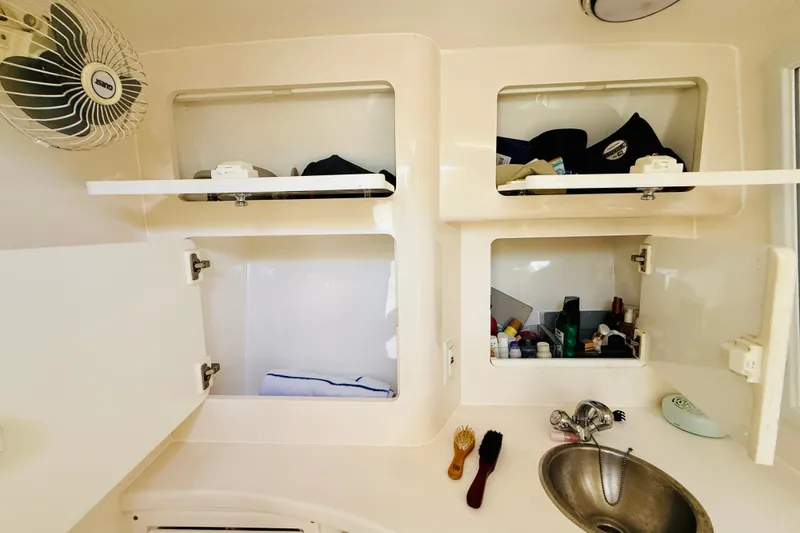Slide: The Image of 2003 Intrepid 377 boat interior with open storage cabinets and sink area. - 90