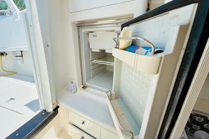 Slide: The Image of Open refrigerator on 2003 Intrepid 377 boat, showing interior shelves and door storage. - 98