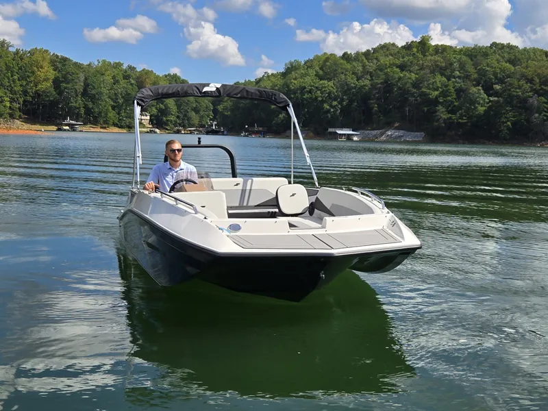 Slide: The Image of A 2027 Starcraft 181SVOB boat on a calm lake with a wooded shoreline in the background. - 28