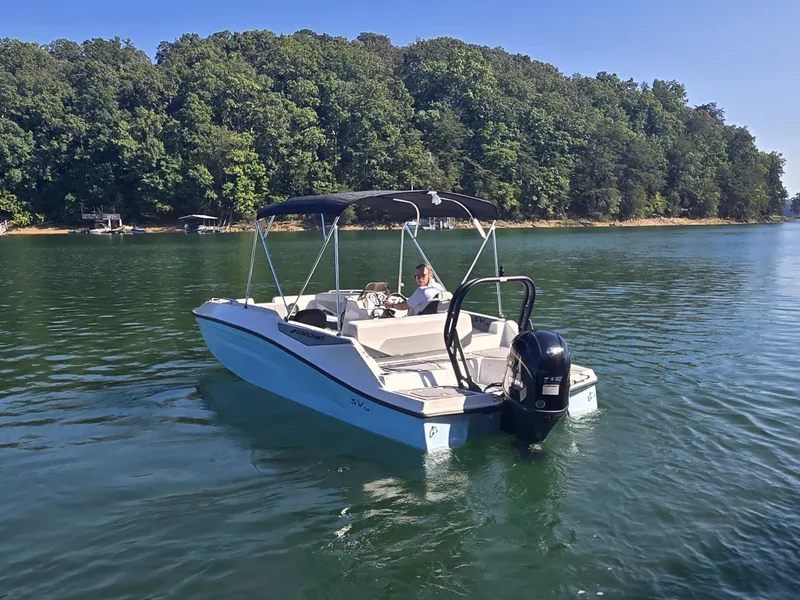 Slide: The Image of A 2027 Starcraft 181SVOB boat on a calm lake with a wooded shoreline in the background. - 24