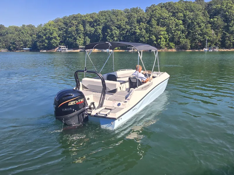 Slide: The Image of A 2027 Starcraft 181SVOB boat on a calm lake with a wooded shoreline in the background. - 5