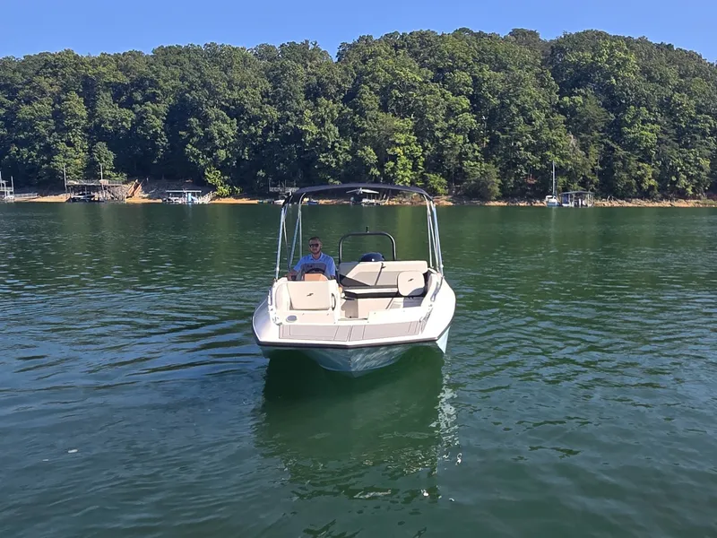 Slide: The Image of A 2027 Starcraft 181SVOB boat on a calm lake with a wooded shoreline. - 2