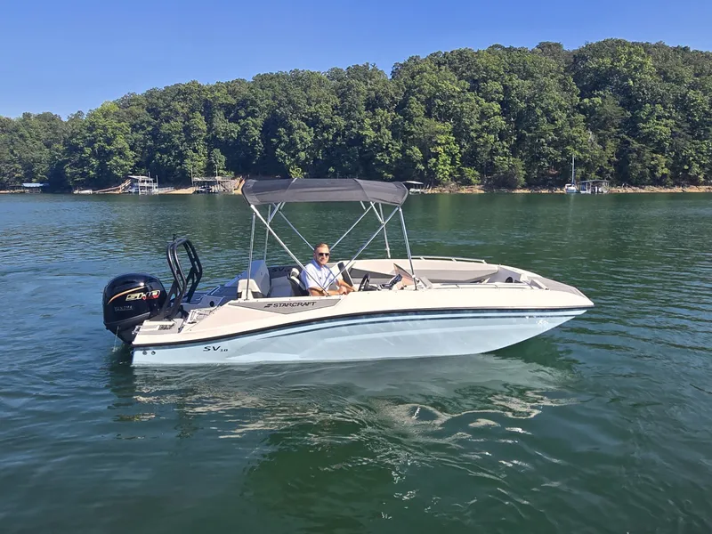 Slide: The Image of A 2027 Starcraft 181SVOB boat on a calm lake with a wooded shoreline in the background. - 4