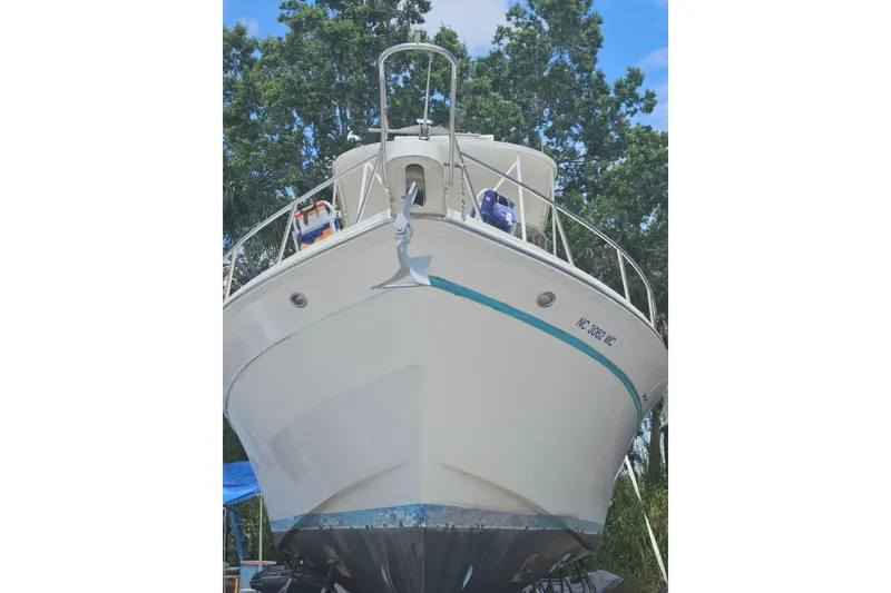 Slide: The Image of 1991 Offshore Yachts 48 Yachtfisher on land, bow view, surrounded by trees. - 4