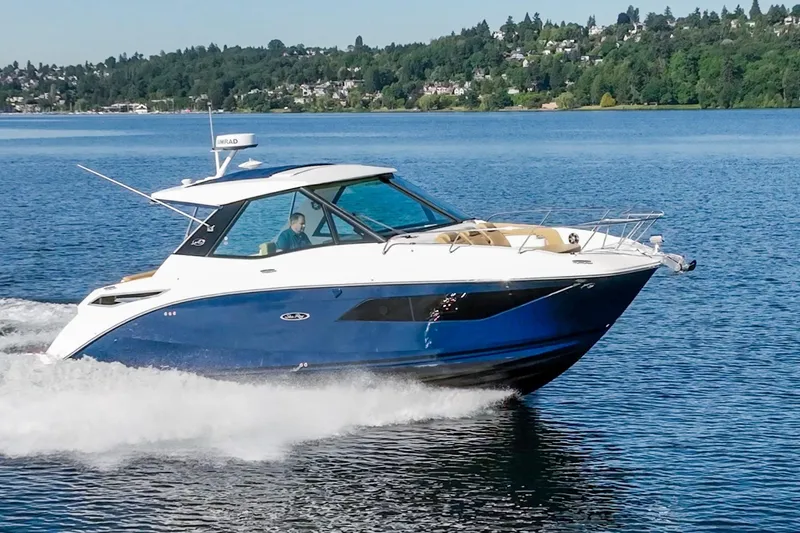 The Image of 2020 Sea Ray Sundancer 320 Coupe cruising on a serene lake with lush green shoreline. - 0