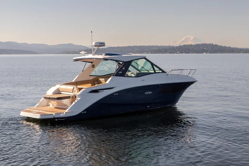 Slide: The Image of 2020 Sea Ray Sundancer 320 Coupe cruising on a serene lake with mountain backdrop. - 43