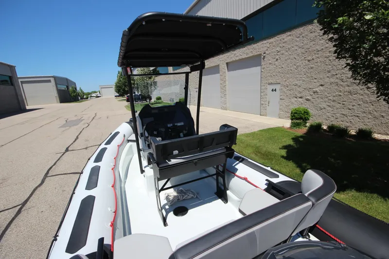 Slide: The Image of 2020 Zodiac Open 6.5 boat parked near industrial buildings under clear blue sky. - 19