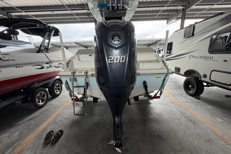 Slide: The Image of 2024 Key West 219 FS boat with 200 HP engine in storage, surrounded by vehicles. - 18