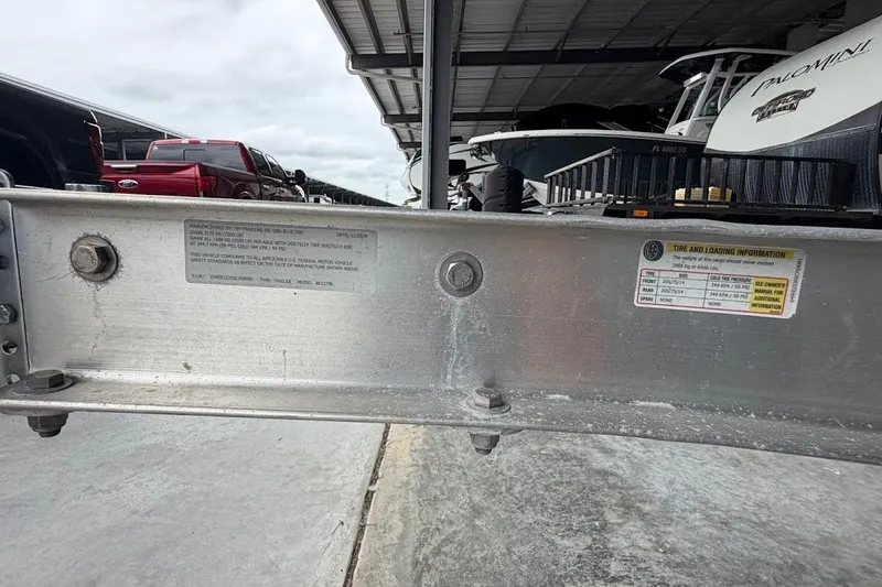 Slide: The Image of Boat trailer with tire and loading information, parked under a shelter with vehicles nearby. - 19